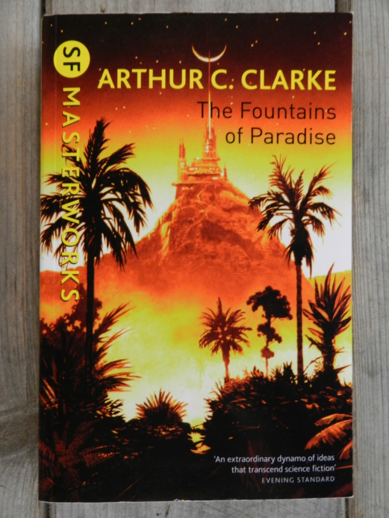The SF Masterworks paperback edition of The Fountains of Paradise by Arthur C. Clarke. The cover shows a mountain at sunset with a building on top of it with a bright line going straight up from it into a stary sky through a crescent moon, with palm trees and other tropical foliage in the foreground.